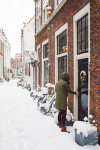 Rear view of woman in snow against buildings in city
