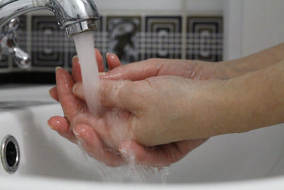Cropped image of woman washing hands in bathroom at home