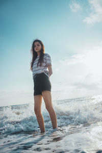 Full length portrait of young woman standing on beach