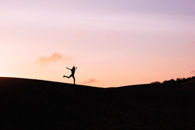 Silhouette woman running in joy against sunset sky at mui ne