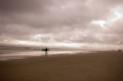 Man standing on beach against sky during sunset