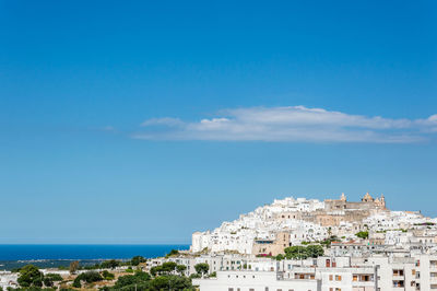 Townscape by sea against blue sky