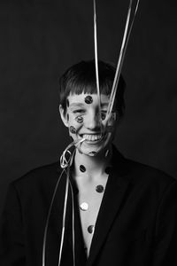 Portrait of young woman wearing mask against black background