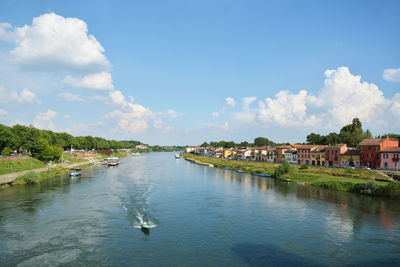 Scenic view of river by buildings against sky