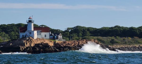 Lighthouse by sea against sky