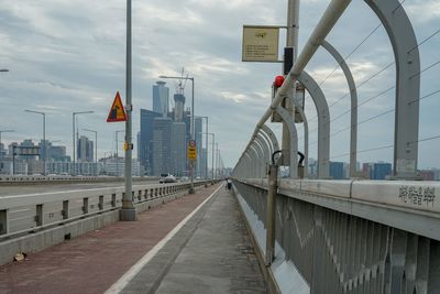 Bridge in city against cloudy sky