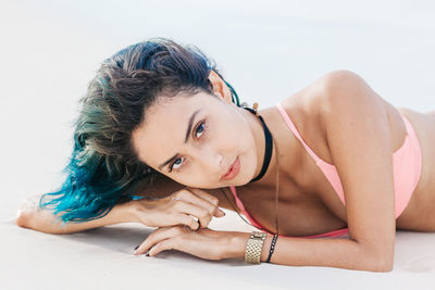 Portrait of woman in bikini lying on shore at beach