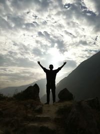 Silhouette man standing on cliff against mountains