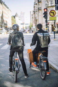 Businessmen with cargo bike and bicycle waiting at traffic signal on road