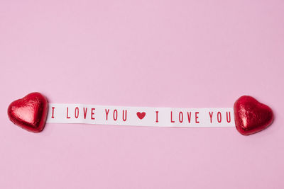 Heart-shaped candies and love message on pink background