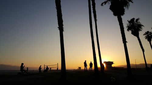 Silhouette people on beach against sky during sunset