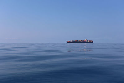 Boat sailing in sea against clear blue sky