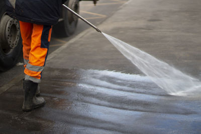 Cleaning up the public place. a jet of water washes the asphalt. disinfection of the bus stop. 