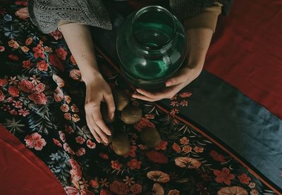 Cropped hand of woman holding container with kiwi on floor