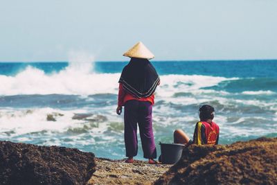 Rear view of man people fishing at beach against sky