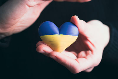 Close-up of hand holding heart shape against black background