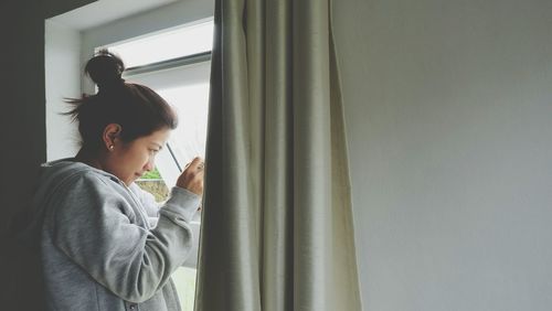 Woman looking through window at home