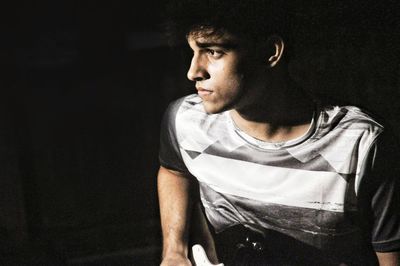 Thoughtful young man against black background