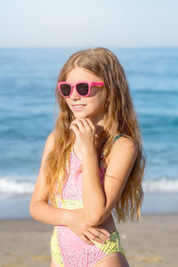 Fashion cute young girl posing on the beach in a summer swimsuit. 