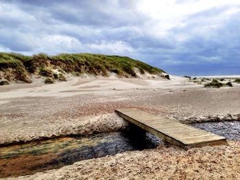 Scenic view of beach against cloudy sky