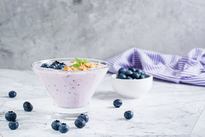 Smoothies with blueberries and granola in a bowl on the table. organic antioxidant healthy food.