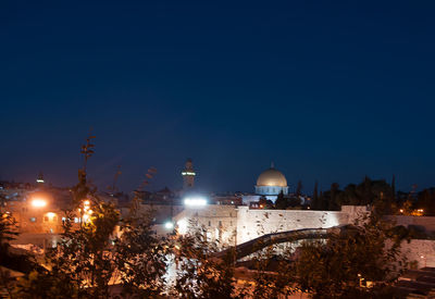 Illuminated buildings against clear blue sky at night