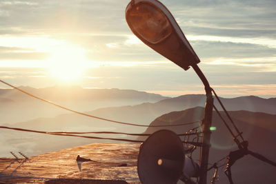 Street light and megaphone against sky during sunset