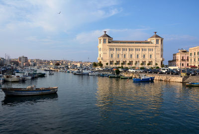 Boats moored in river against buildings in city