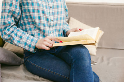 Midsection of man sitting on sofa at home