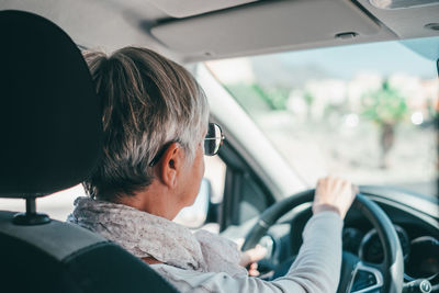 Senior woman driving car on sunny day