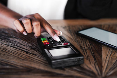 Close up of woman doing contact less payment with mobile phone in cafe. technology and shopping