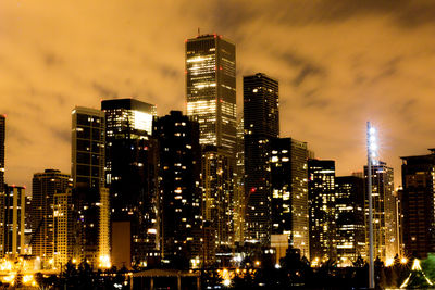 Illuminated buildings in city against sky at night