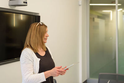 Businesswoman using digital tablet while standing in office