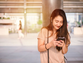 Portrait of a smiling young woman using mobile phone outdoors