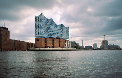 Hamburg, elbe philharmonic hall from the water with  view of  harbor and hafencity under cloudy sky
