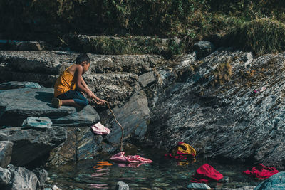 Rear view of men sitting on rock