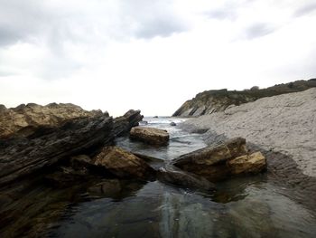 Rock formations by sea against sky