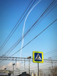 Low angle view of cables against vapor in blue sky