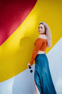 Portrait of woman standing against yellow wall