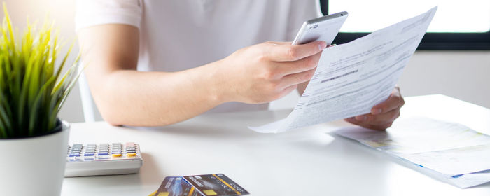 Midsection of woman holding paper