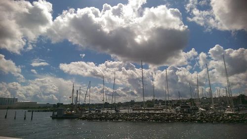 Sailboats in harbor against sky