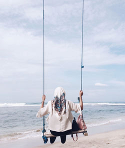 Rear view of woman on beach against sky