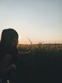 Woman standing on field against sky during sunset