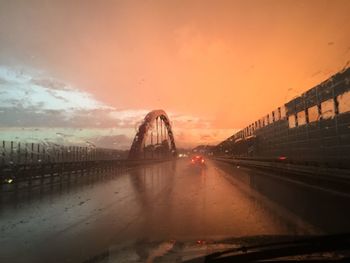 Bridge over illuminated city against sky at sunset