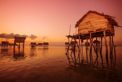 Built structure by lake against sky during sunset