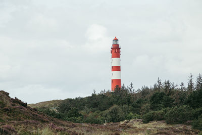 Lighthouse by sea against sky