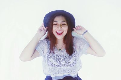 Portrait of young woman standing against white background