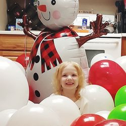 Portrait of happy girl with balloons at store