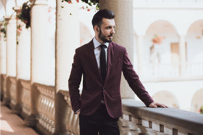 Well-dressed thoughtful man looking away while standing in corridor