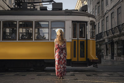 Woman standing by train on street in city